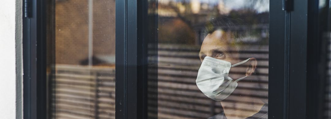 Hombre mira por la ventana durante la crisis sanitaria del Covid 19 Hombre mira por la ventana durante la crisis sanitaria del Covid 19