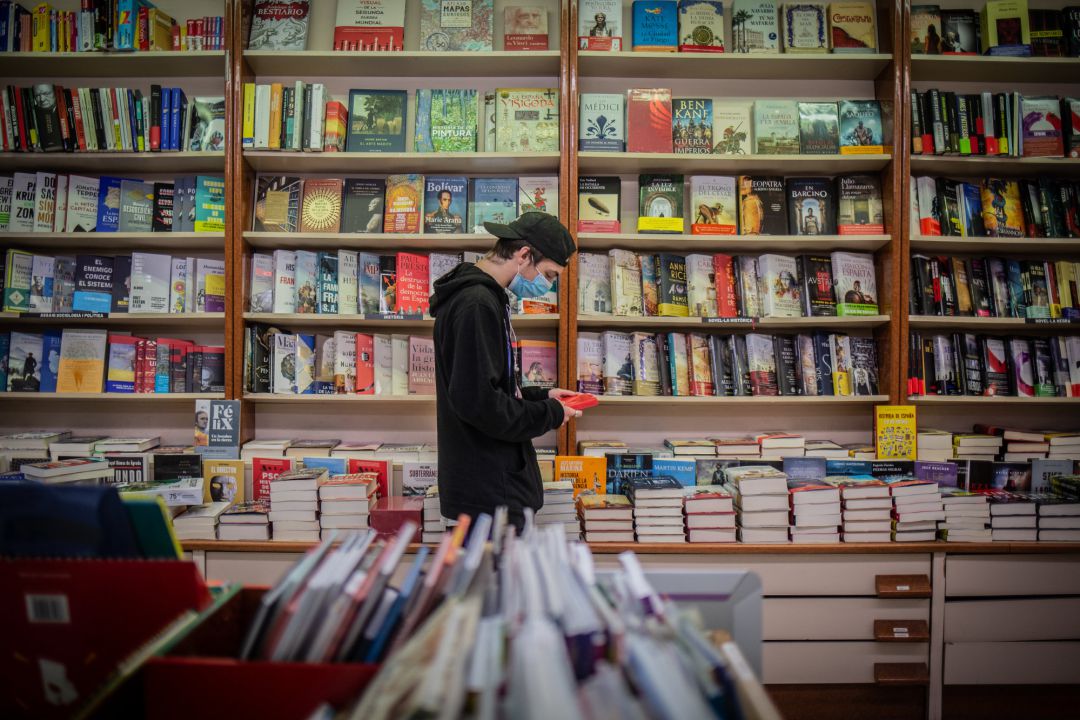 Un joven observa un libro en una librería Un joven observa un libro en una librería