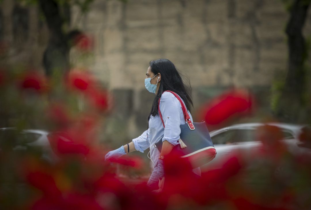 Una mujer andando por Sevilla con mascarilla y guantes Una mujer andando por Sevilla con mascarilla y guantes