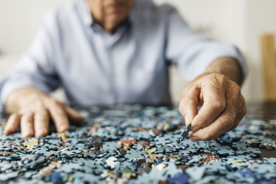 Una persona mayor trabaja en la confeción de un puzzle. Una persona mayor trabaja en la confeción de un puzzle.