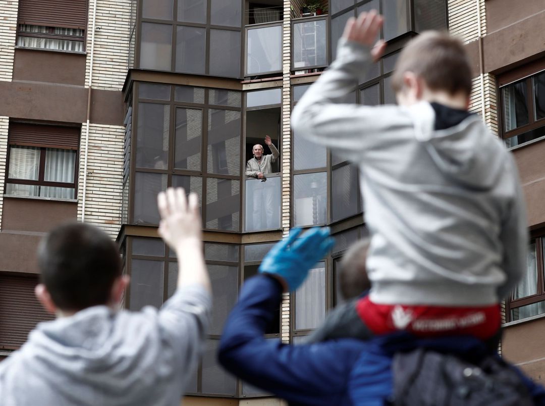 Dos niños saludan a su abuelo asomado a la ventana en una día donde acaba el confinamiento para los menores de 14 años que pueden salir a la calle. Dos niños saludan a su abuelo asomado a la ventana en una día donde acaba el confinamiento para los menores de 14 años que pueden salir a la calle.