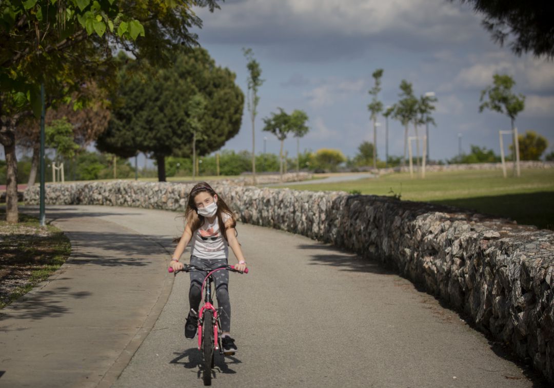 Una niña con mascarilla monta en bicicleta por el parque en el tercer día de desconfinamiento de niños. Una niña con mascarilla monta en bicicleta por el parque en el tercer día de desconfinamiento de niños.