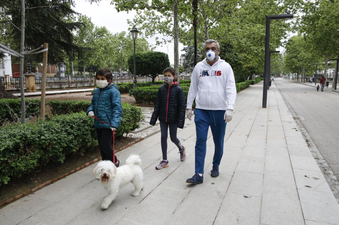 Dos niños con mascarillas acompañados por su padre pasean al perro ,en Granada. Dos niños con mascarillas acompañados por su padre pasean al perro ,en Granada.