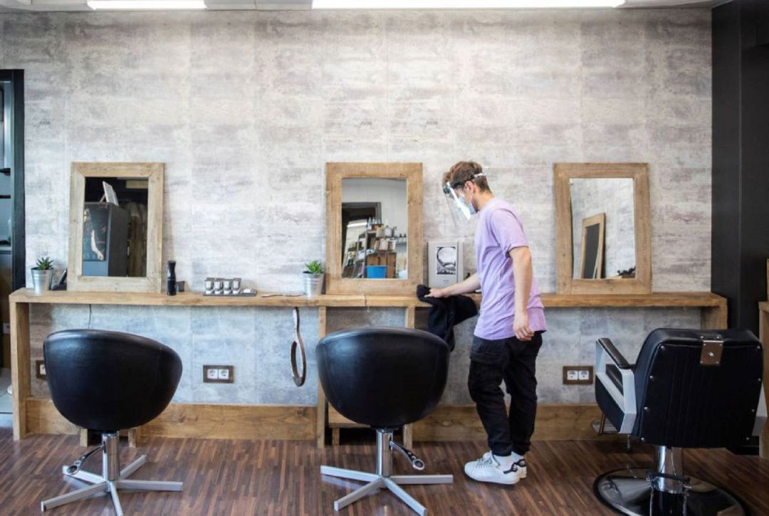 Un empleado de peluquería desinfectando la zona de corte Un empleado de peluquería desinfectando la zona de corte