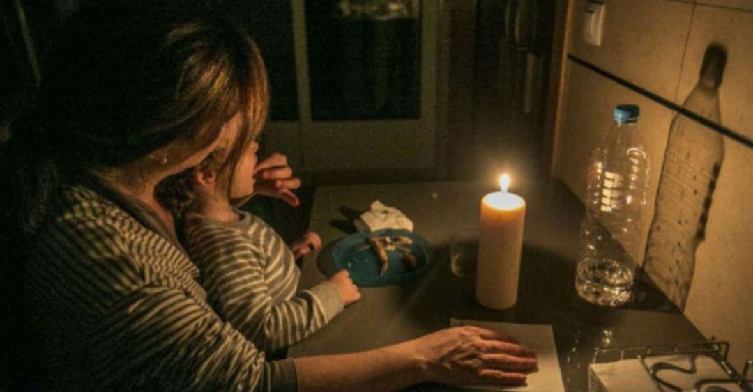 Una madre da de comer a su hija a la luz de una vela Una madre da de comer a su hija a la luz de una vela