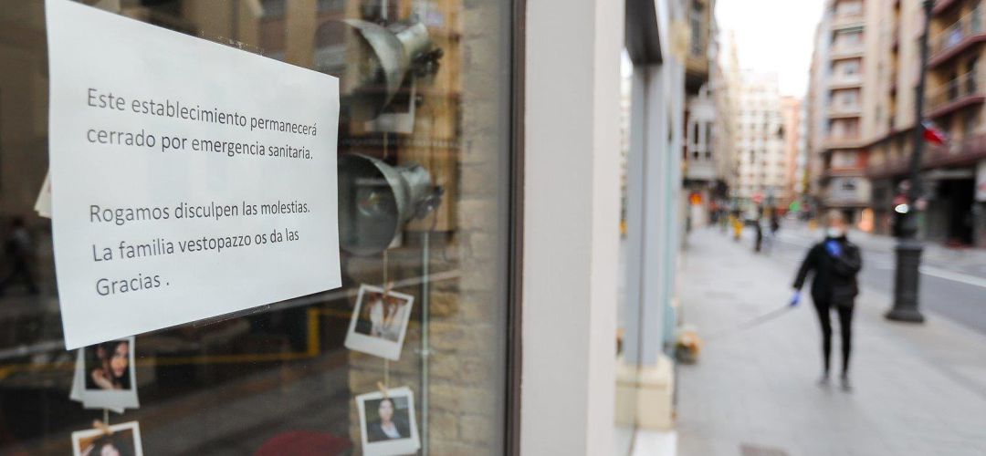Cartel en la ventana de un establecimiento cerrado en una calle prácticamente vacía Cartel en la ventana de un establecimiento cerrado en una calle prácticamente vacía