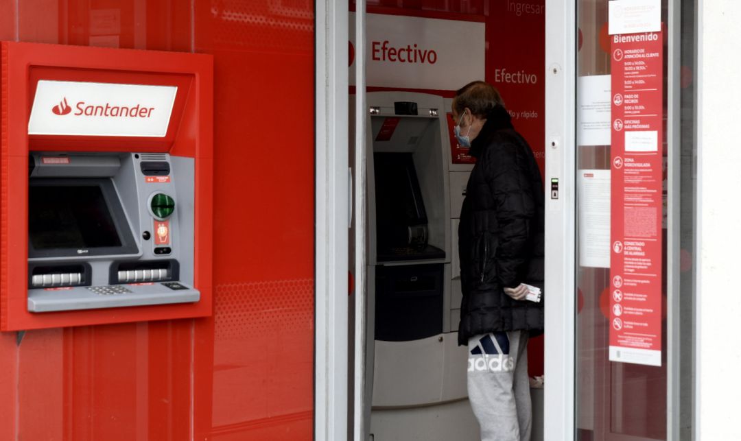 Un hombre saca dinero de un cajero del Banco Santander. Un hombre saca dinero de un cajero del Banco Santander.