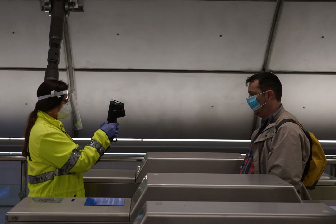 Una voluntaria de la DYA toma la temperatura con una pistola a un viajero en la estación de metro de Otxarkoaga Una voluntaria de la DYA toma la temperatura con una pistola a un viajero en la estación de metro de Otxarkoaga