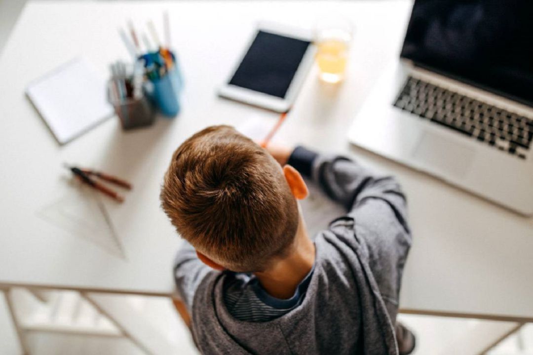 Niño haciendo tareas con el apoyo de la tecnología Niño haciendo tareas con el apoyo de la tecnología