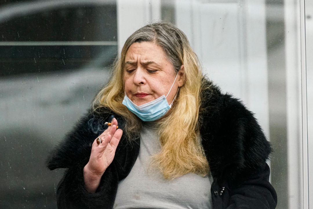 Una mujer fuma un cigarro en la calle durante la crisis del coronavirus Una mujer fuma un cigarro en la calle durante la crisis del coronavirus