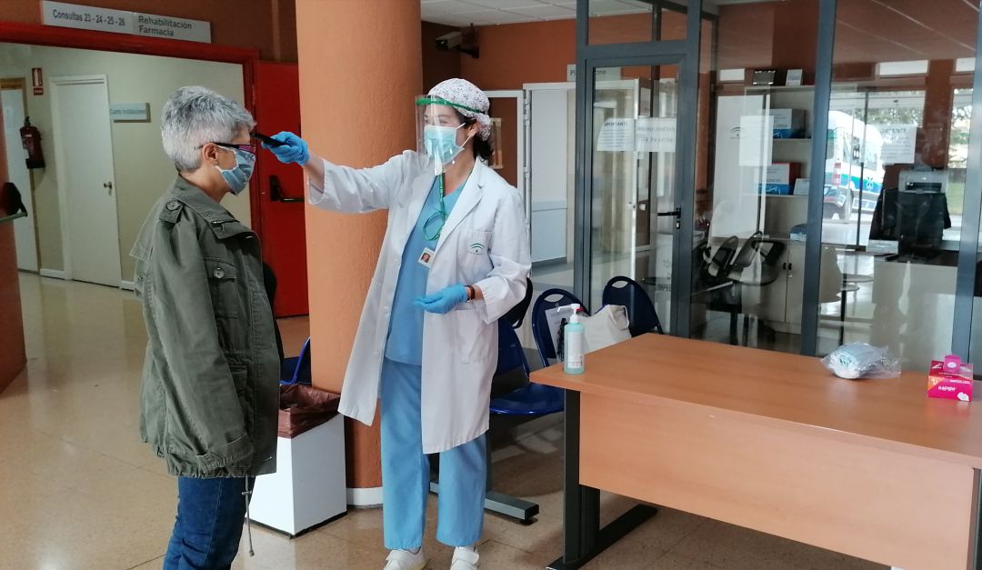 Auxiliar de enfermería toma la temperatura a una persona que llega al hospital Auxiliar de enfermería toma la temperatura a una persona que llega al hospital