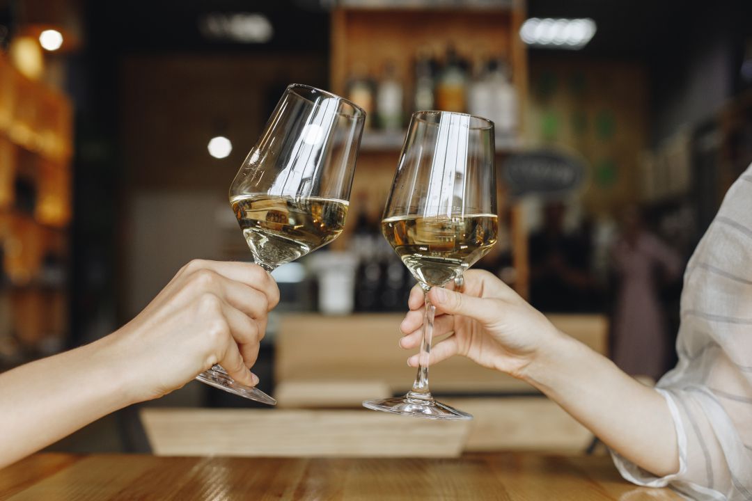 Dos personas brindan con vino blanco Dos personas brindan con vino blanco