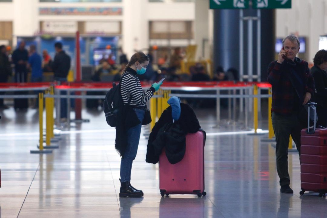 Una turista con mascarilla y guantes en el aeropuerto Una turista con mascarilla y guantes en el aeropuerto
