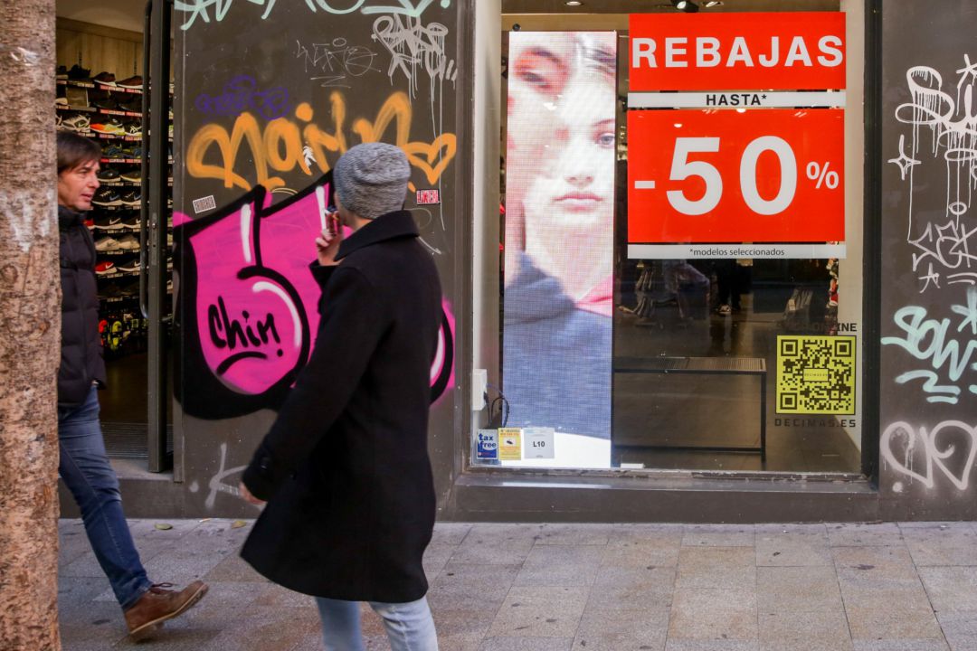 Dos hombres pasean junto a una tienda en Madrid, en la que se ofertan rebajas de hasta un 50%. Dos hombres pasean junto a una tienda en Madrid, en la que se ofertan rebajas de hasta un 50%.