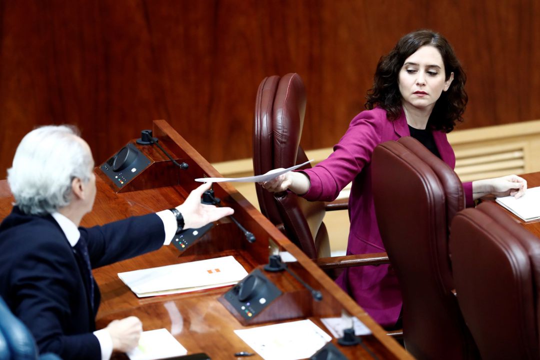 La presidenta de la Comunidad de Madrid, Isabel Díaz Ayuso le entrega un papel al consejero de Sanidad, Enrique Ruiz Escudero durante la sesión. La presidenta de la Comunidad de Madrid, Isabel Díaz Ayuso le entrega un papel al consejero de Sanidad, Enrique Ruiz Escudero durante la sesión.