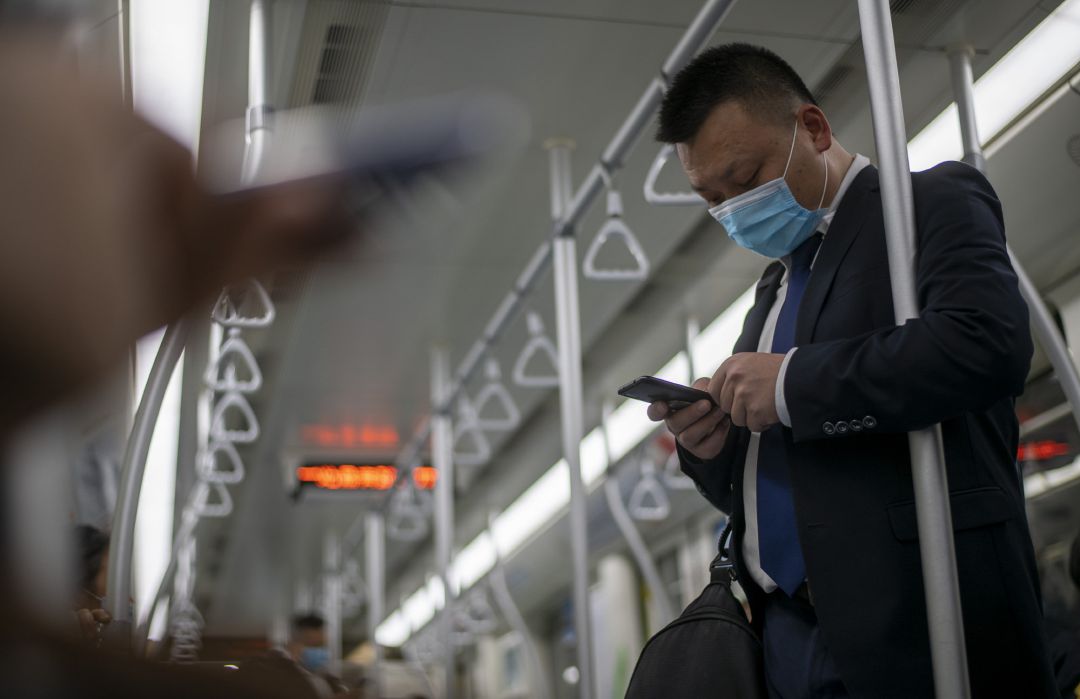 Un hombre protegido con mascarilla se apoya en la barra de un vagón de metro mientras utiliza su teléfono móvil sin guantes en la ciudad de Shanghái (China). Un hombre protegido con mascarilla se apoya en la barra de un vagón de metro mientras utiliza su teléfono móvil sin guantes en la ciudad de Shanghái (China).
