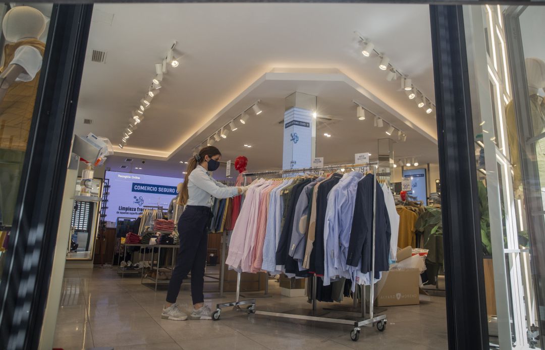 Una empleada de una tienda de ropa con mascarilla y guantes, en Sevilla Una empleada de una tienda de ropa con mascarilla y guantes, en Sevilla