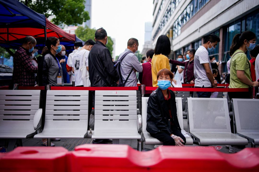 Una mujer espera sentada a las colas para pasar el test del coronavirus en Wuhan Una mujer espera sentada a las colas para pasar el test del coronavirus en Wuhan
