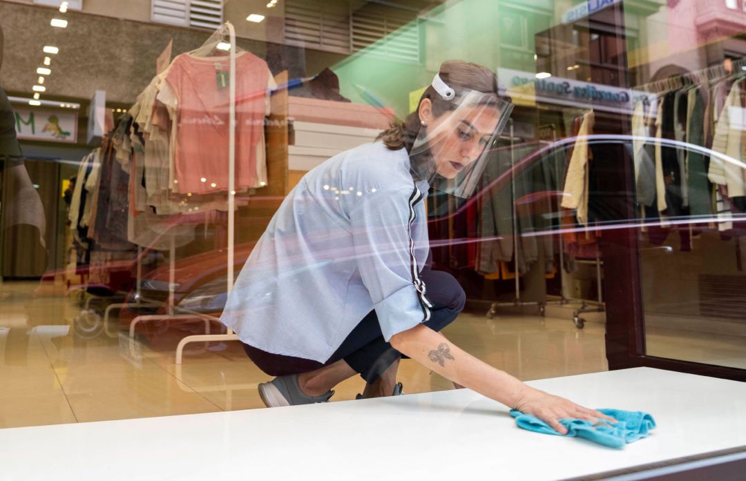 Una dependienta limpia el escaparate de una tienda de complementos y ropa que ya ha abierto sus puertas. Una dependienta limpia el escaparate de una tienda de complementos y ropa que ya ha abierto sus puertas.