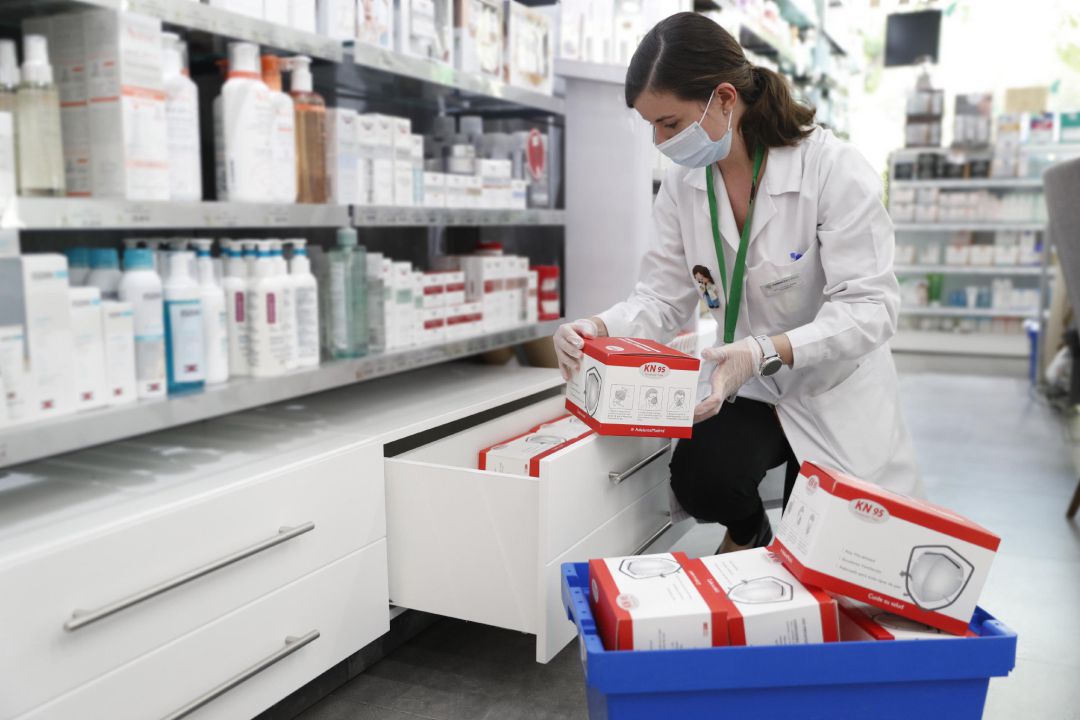 Una farmacéutica coloca cajas con mascarillas. Una farmacéutica coloca cajas con mascarillas.