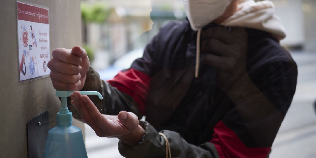 Un hombre se limpia las manos con gel hidroalcohólico antes de entrar a una tienda Un hombre se limpia las manos con gel hidroalcohólico antes de entrar a una tienda