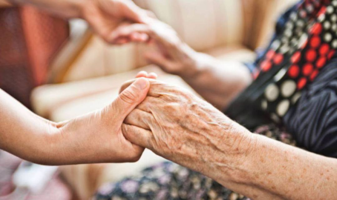 Una trabajadora ayuda a una anciana a levantarse en una residencia Una trabajadora ayuda a una anciana a levantarse en una residencia