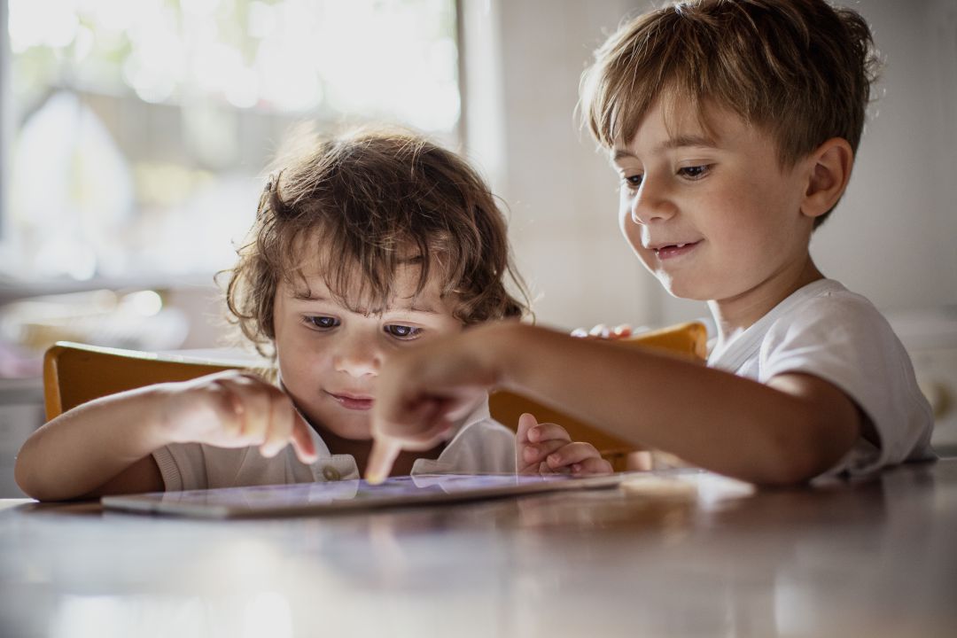 Dos pequeños juegan con una tablet. Dos pequeños juegan con una tablet.