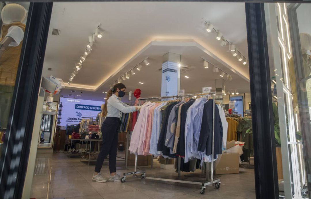 Una empleada de una tienda se prepara para la apertura del establecimiento Una empleada de una tienda se prepara para la apertura del establecimiento