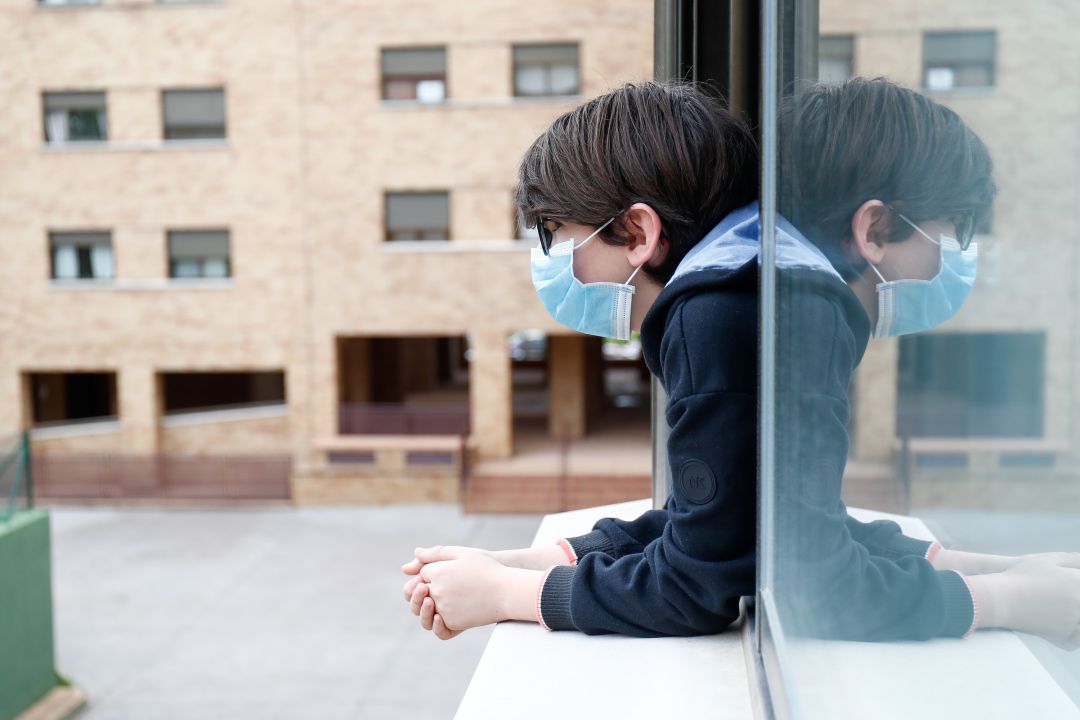 Un niño se asoma desde la ventana de su casa Un niño se asoma desde la ventana de su casa