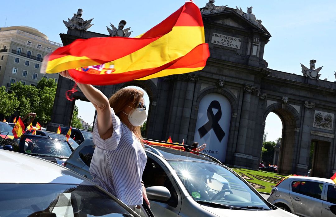 Una mujer levanta una bandera de España desde un coche en la manifestación promovida por Vox en Madrid contra la gestión del Gobierno en la pandemia del coronavirus. Una mujer levanta una bandera de España desde un coche en la manifestación promovida por Vox en Madrid contra la gestión del Gobierno en la pandemia del coronavirus.