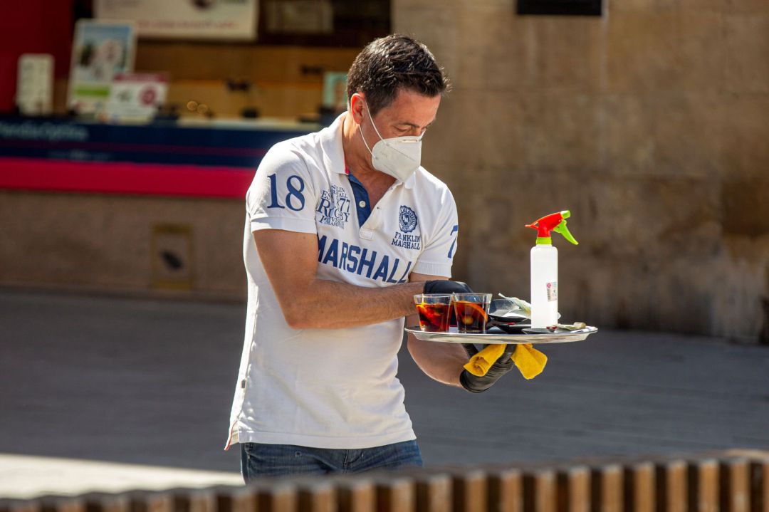 Un camarero atiende una mesa equipado con mascarilla y con un espray desinfectante en el centro de Vitoria
Un camarero atiende una mesa equipado con mascarilla y con un espray desinfectante en el centro de Vitoria