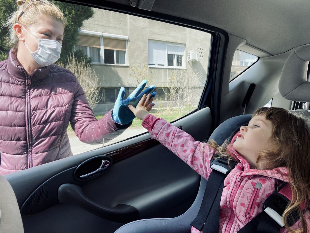 Una niña saluda a través del cristal a su abuela Una niña saluda a través del cristal a su abuela