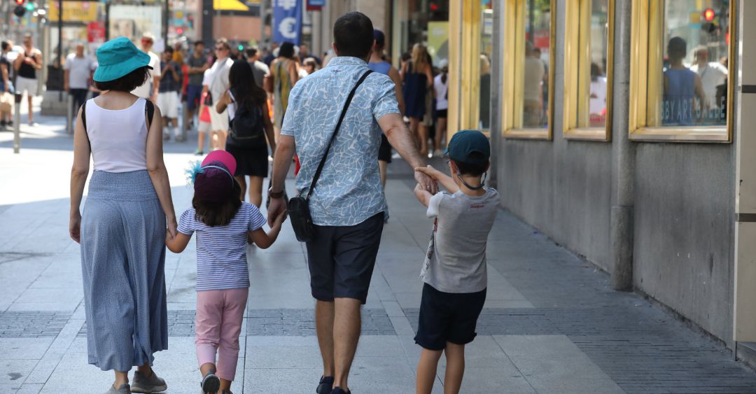 Una familia pasea de la mano por una calle Una familia pasea de la mano por una calle