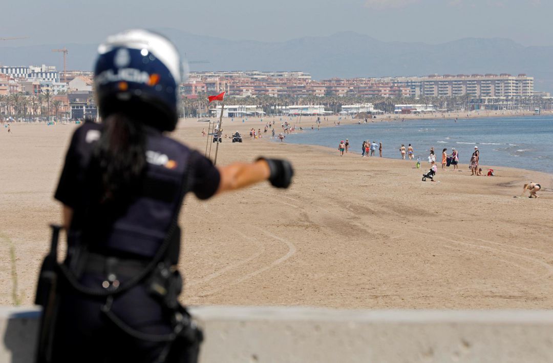 Una agente de la Policia Nacional realiza labores de control en la playa de la Malvarrosa durante la fase 1 de la desescalada en València. Una agente de la Policia Nacional realiza labores de control en la playa de la Malvarrosa durante la fase 1 de la desescalada en València.