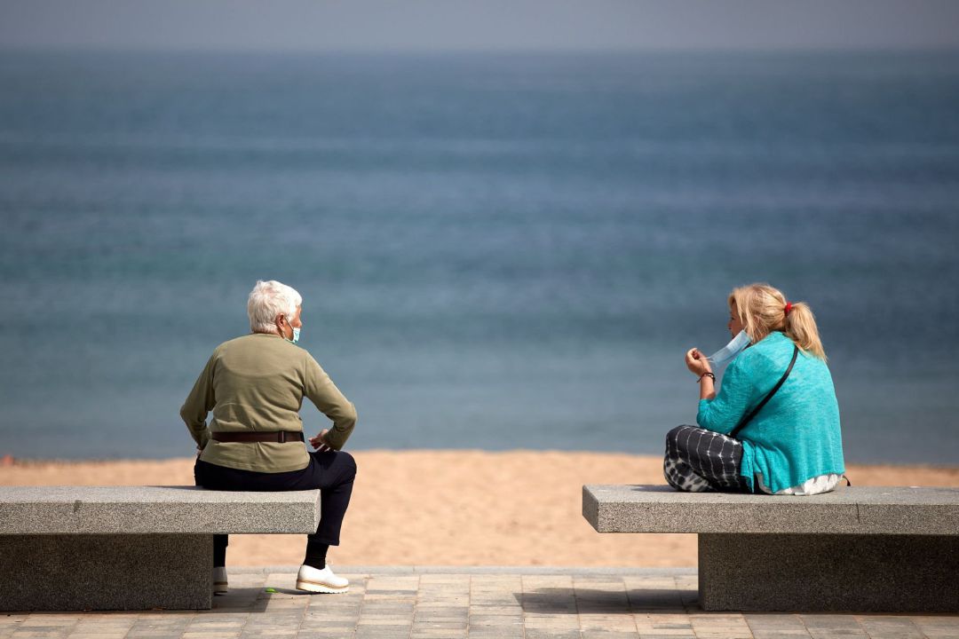 Dos mujeres hablan en unos bancos de la playa de L'Escala (Girona) este jueves mientras Girona se mantiene en la fase 1 de la desescalada. Dos mujeres hablan en unos bancos de la playa de L'Escala (Girona) este jueves mientras Girona se mantiene en la fase 1 de la desescalada.