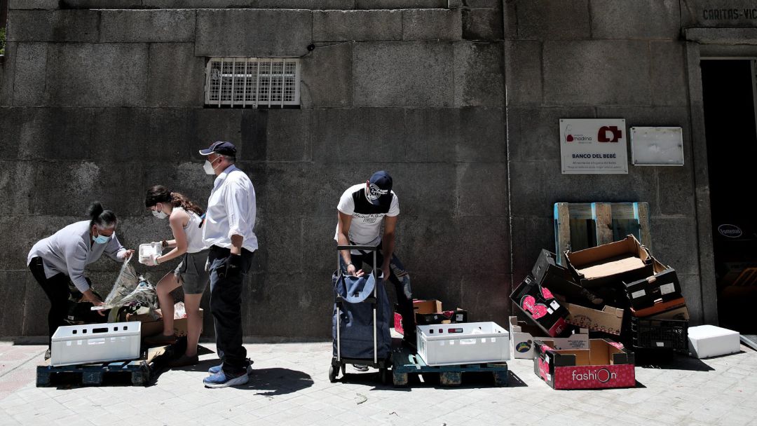 Dos personas recogen alimentos (izquierda y derecha) que les dan dos voluntarios a las puertas de la Parroquia Santa María Micaela en Madrid (España), a 29 de mayo de 2020. Dos personas recogen alimentos (izquierda y derecha) que les dan dos voluntarios a las puertas de la Parroquia Santa María Micaela en Madrid (España), a 29 de mayo de 2020.