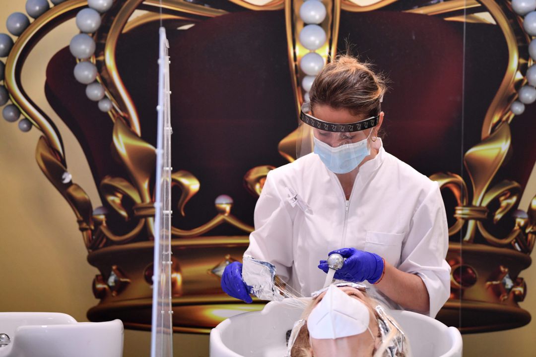 Una peluquera trabajando con mascarilla y guantes en una peluquería de Roma Una peluquera trabajando con mascarilla y guantes en una peluquería de Roma