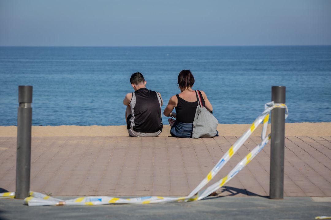 Dos jóvenes sentados en el Paseo Marítimo de la Playa de la Barceloneta Dos jóvenes sentados en el Paseo Marítimo de la Playa de la Barceloneta