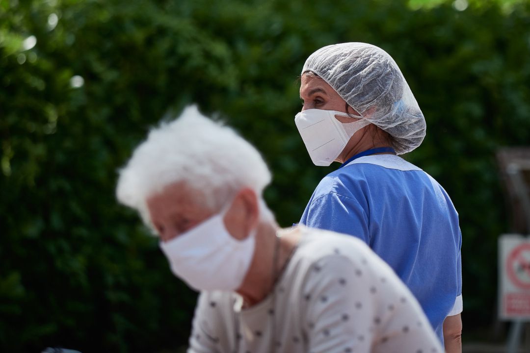 Una residente y una trabajadora sanitaria, ambas protegidas con mascarilla. Una residente y una trabajadora sanitaria, ambas protegidas con mascarilla.