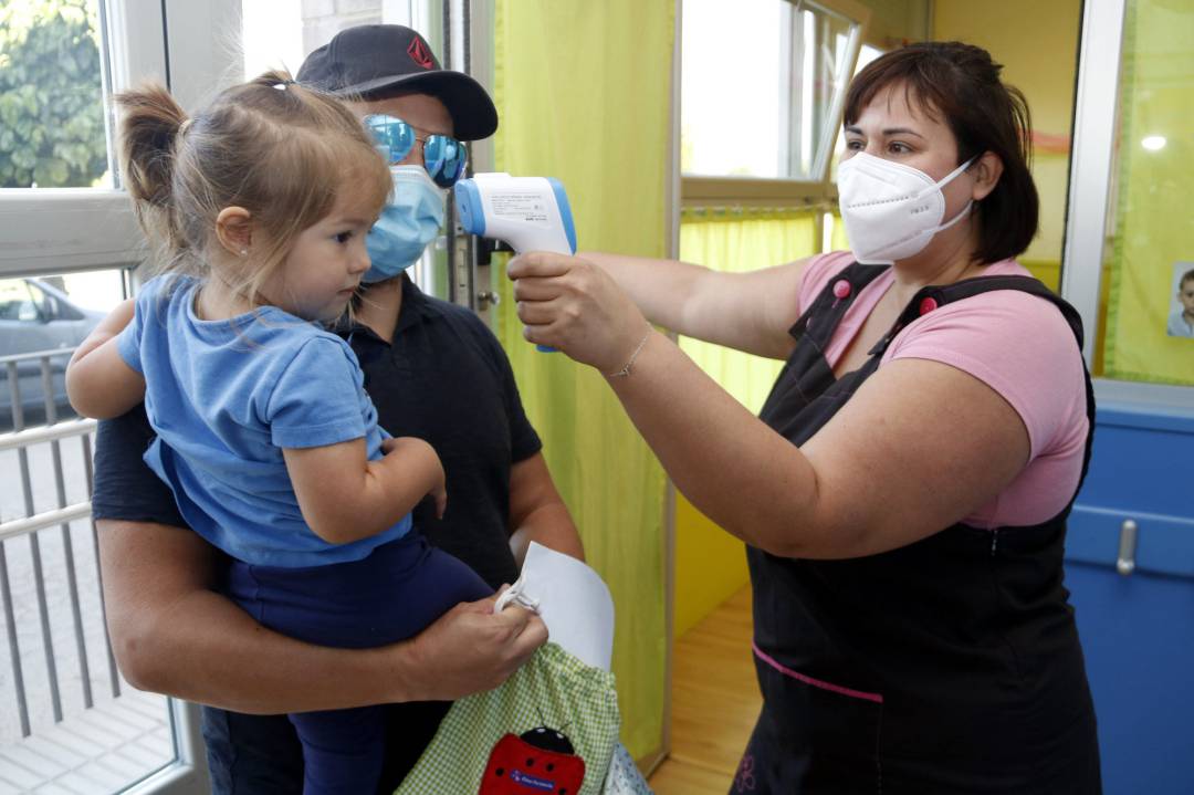 Una professora mesurant la temperatura a una nena que acaba d'arribar al centre, el 8 de juny de 2020 Una professora mesurant la temperatura a una nena que acaba d'arribar al centre, el 8 de juny de 2020