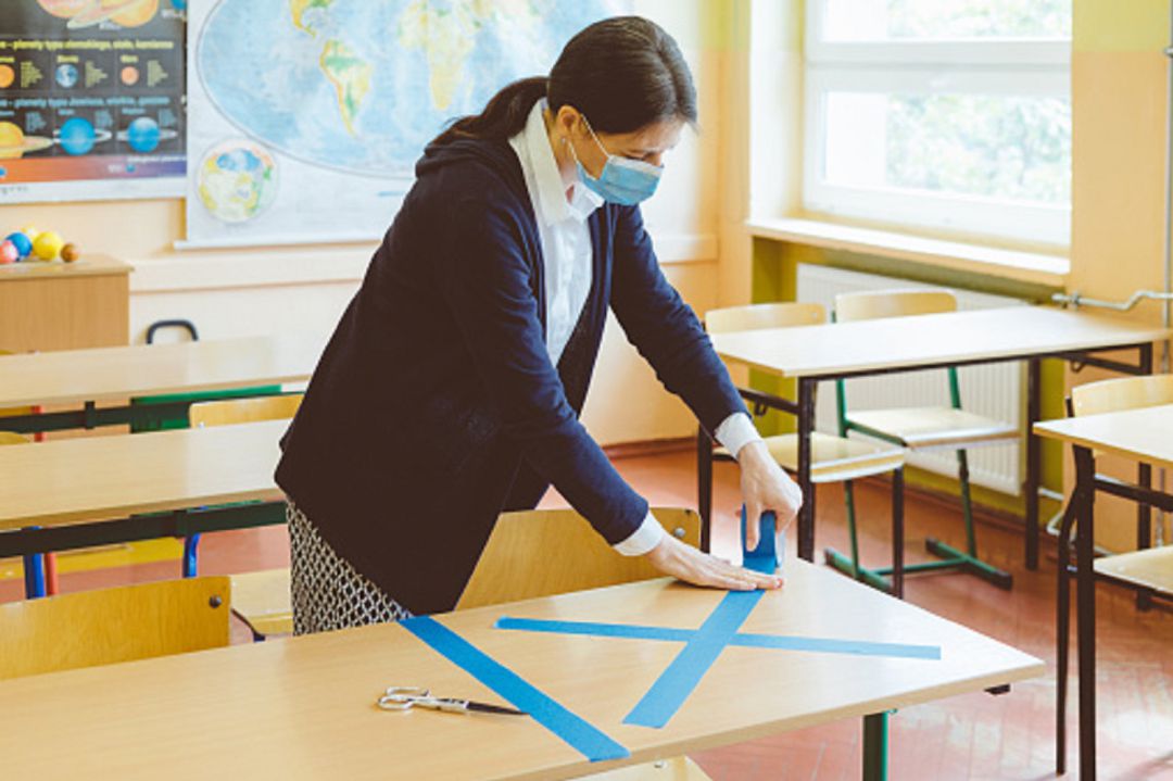Maestra marcando medidas de seguridad en un aula Maestra marcando medidas de seguridad en un aula