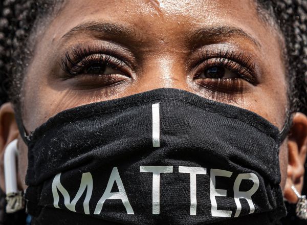 Una mujer con mascarilla en la que puede leerse un mensaje en referencia al movimiento Black lives matter.