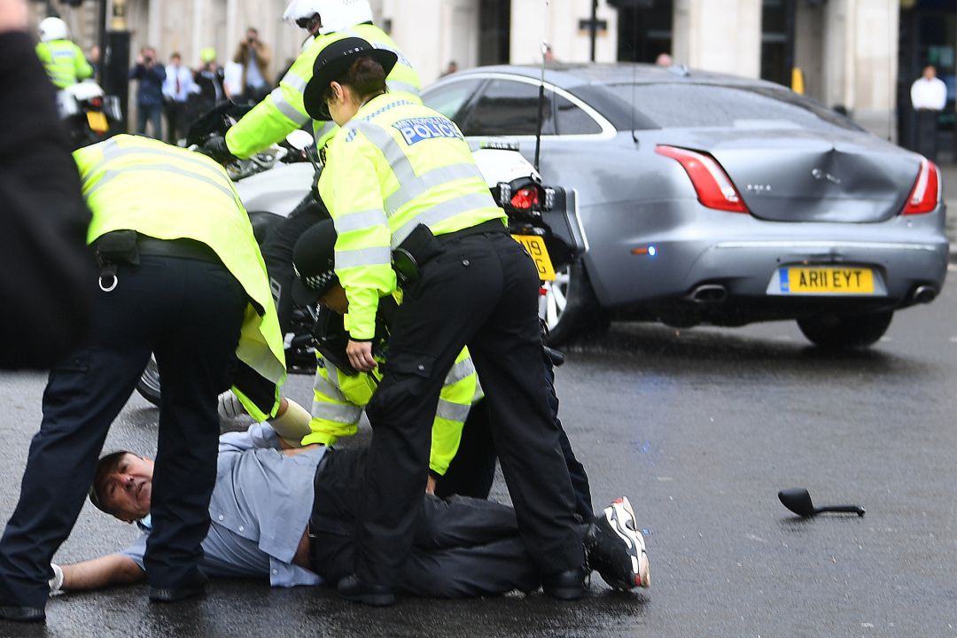 Un grupo de policías arrestan al manifestante que se ha colocado delante del coche de Boris Johnson y ha causado un accidente de tráfico Un grupo de policías arrestan al manifestante que se ha colocado delante del coche de Boris Johnson y ha causado un accidente de tráfico