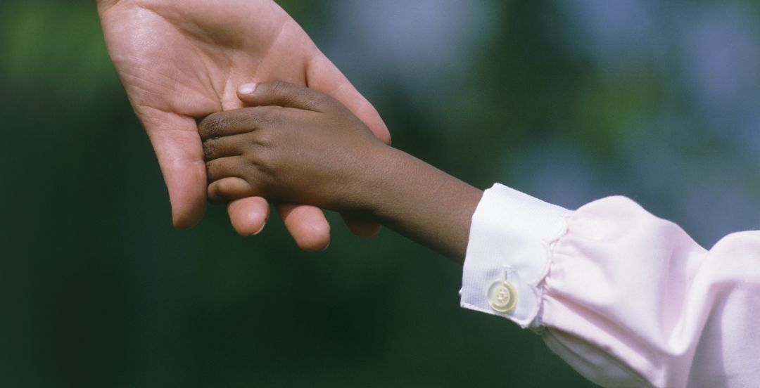 Un niño coge de la mano a un adulto. Un niño coge de la mano a un adulto.