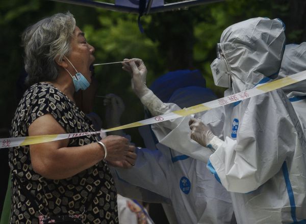 Una trabajadora de los servicios de control epidemiológico de China realiza la prueba de coronavirus a una mujer en Beijing.