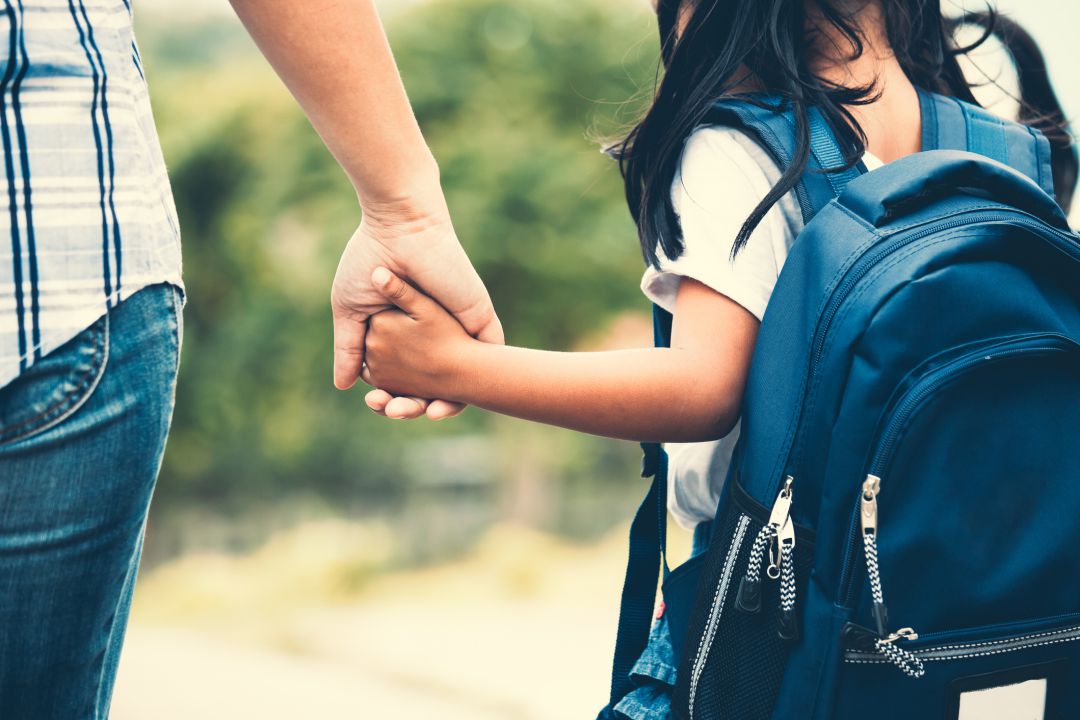 Niña va al colegio de la mano de su madre Niña va al colegio de la mano de su madre