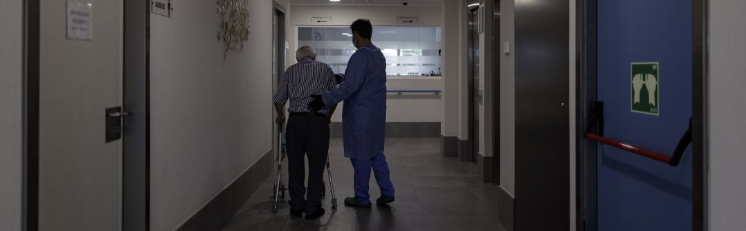 Un técnico sociosanitario delun cesntro de mayores ayuda a un usuario Un técnico sociosanitario delun cesntro de mayores ayuda a un usuario