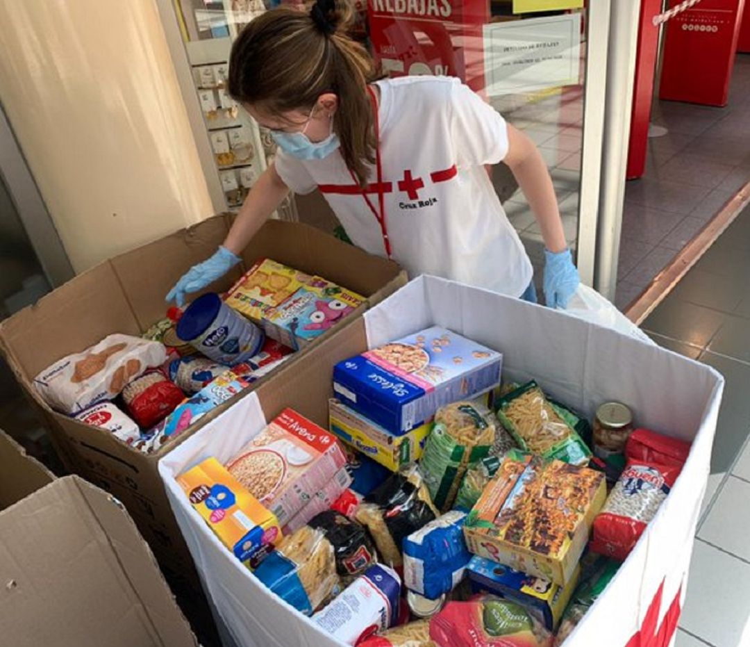 Una voluntaria de Cruz Roja colocando en uno de los contenedores alimentos donados Una voluntaria de Cruz Roja colocando en uno de los contenedores alimentos donados