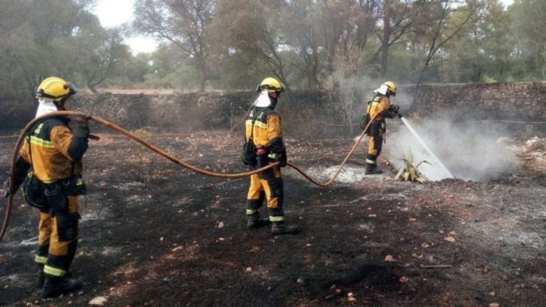Bomberos refrescando una zona incendiada Bomberos refrescando una zona incendiada