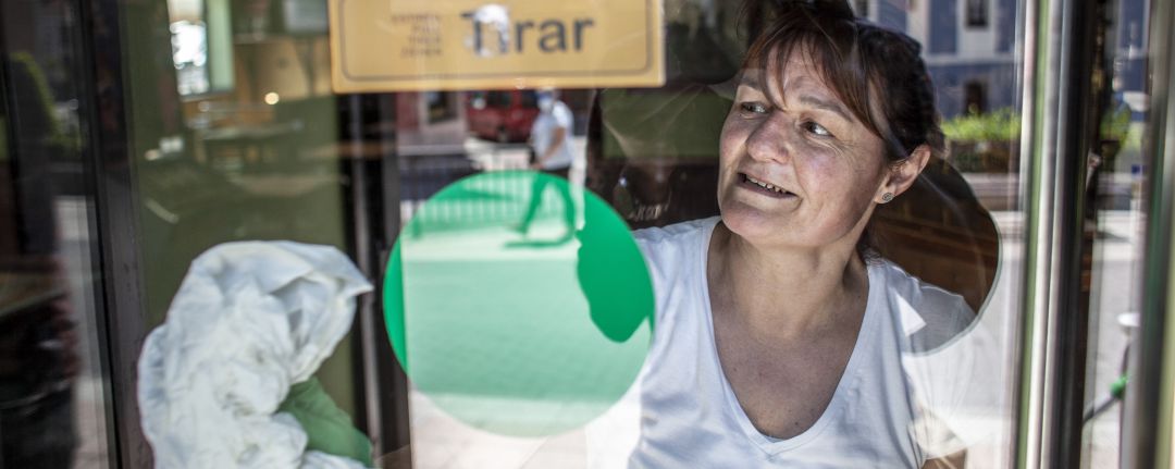 Mujer limpiando la puerta de su negocio Mujer limpiando la puerta de su negocio